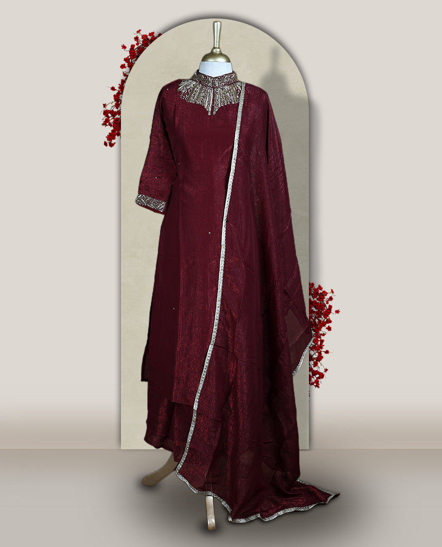 Deep Maroon colour churidar set with a rich sheen, beautifully adorned with golden cut beads work on the neckline and sleeve borders, Paired with a matching dupatta featuring a subtle zari edge, perfect for a regal festive look.