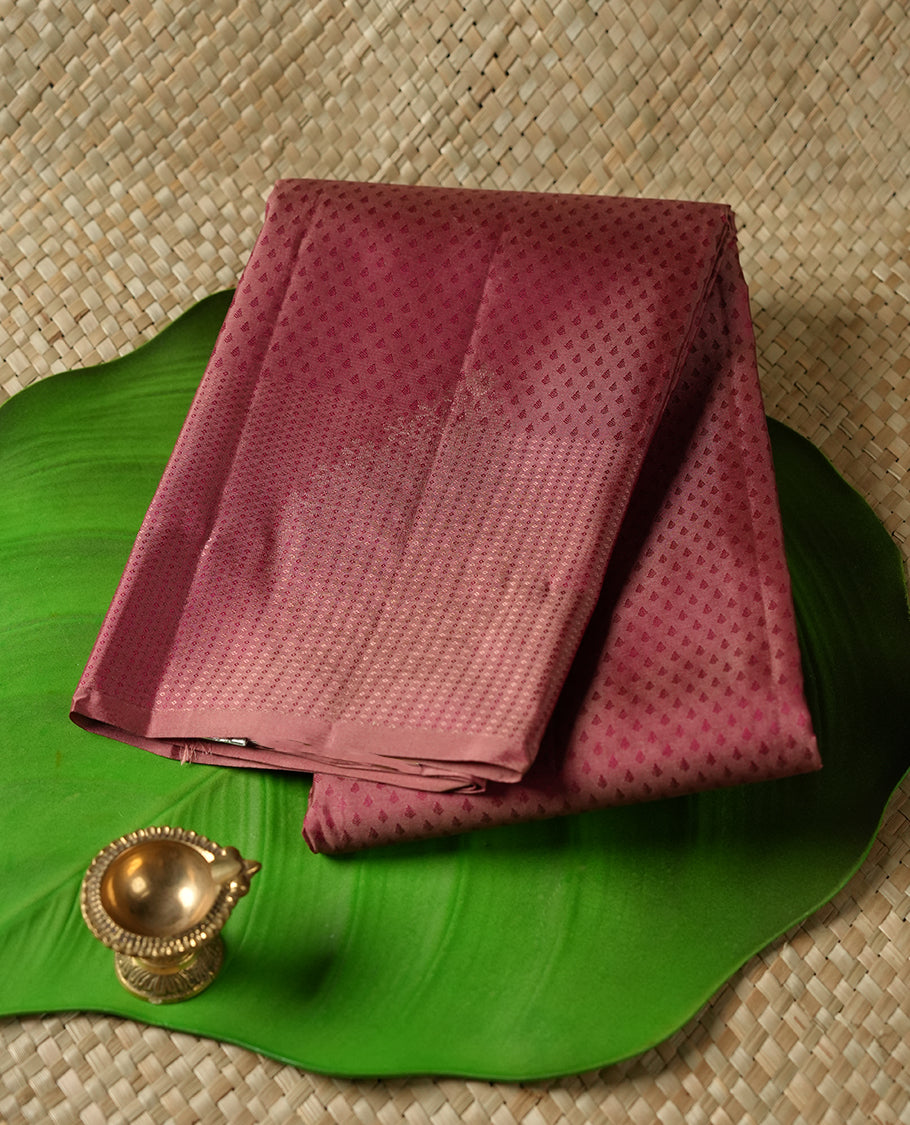Dark mauve colour Vasundhara silk saree adorned with all-over tiny motifs on the body, complemented by a self colour with tiny diamond pattern with gold tree motifs on border and paired with a matching blouse piece.