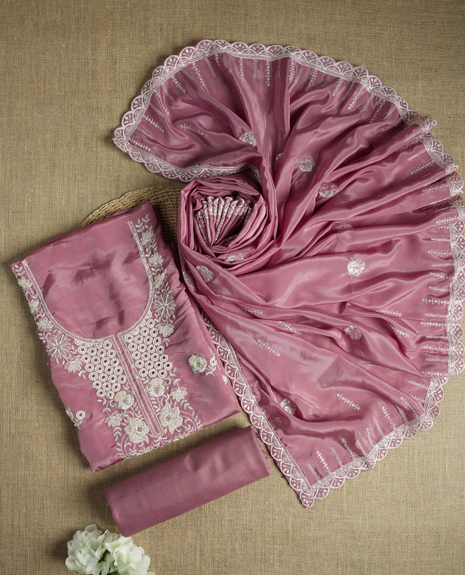Dusty mauve colour suit material adorned with elegant white thread , cut beads & sequin embroidery, highlighted by a delicate lace border & Paired with a matching embroidered dupatta and plain bottom.
