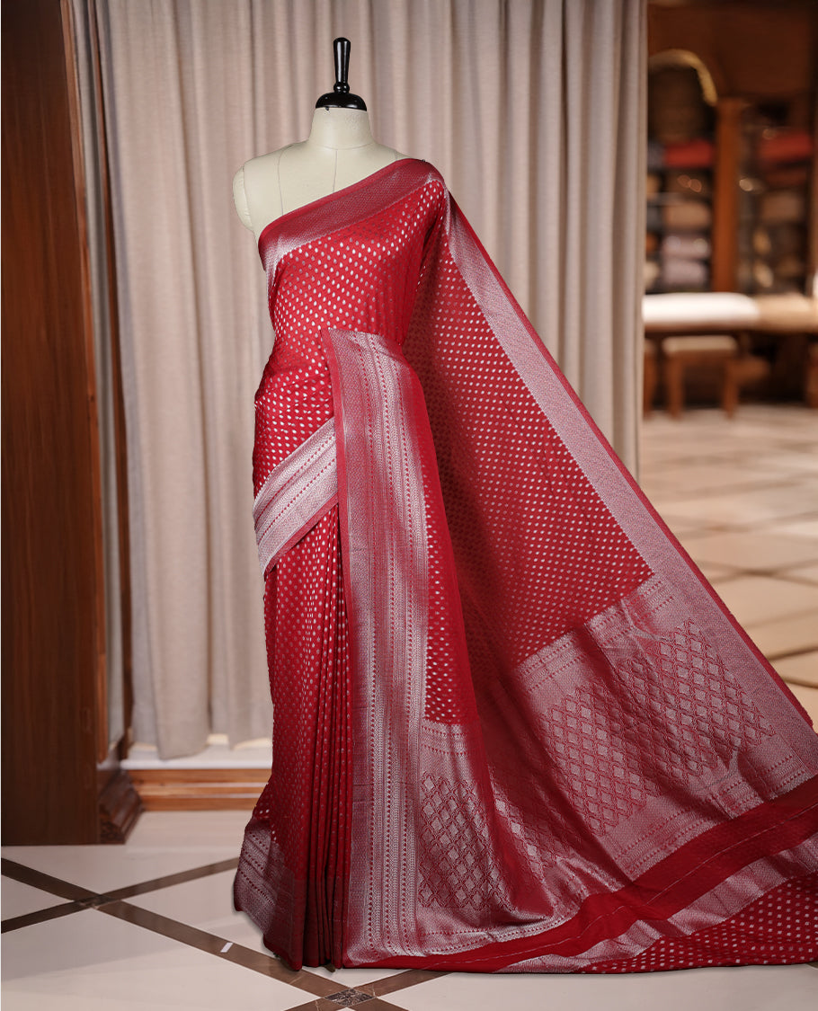 Maroon colour Banarasi silk saree featuring intricate zari weaving and a soft silk texture, Adorned with silver motifs on the body, complemented by a rich Banarasi border and pallu & Comes with a matching blouse.