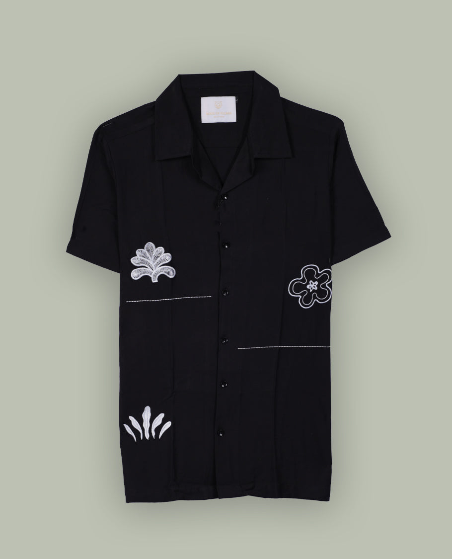 Black colour shirt featuring elegant white embroidery motifs on the body, Designed with a classic shirt collar and short sleeves, it blends contemporary style with subtle detailing.