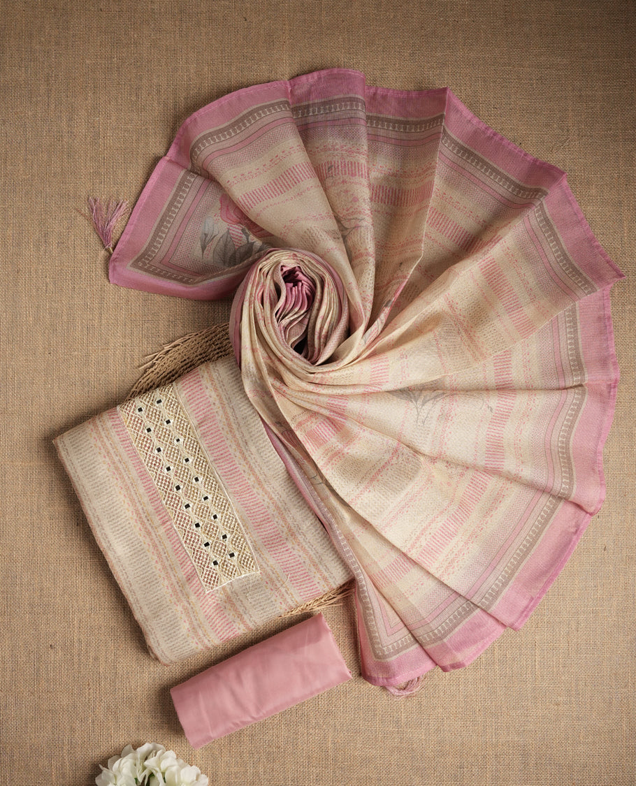 Pastel pink and beige colour suit material with delicate woven mirror work patterns and subtle zari detailing & Includes a soft dupatta with a floral touch and plain matching bottom.