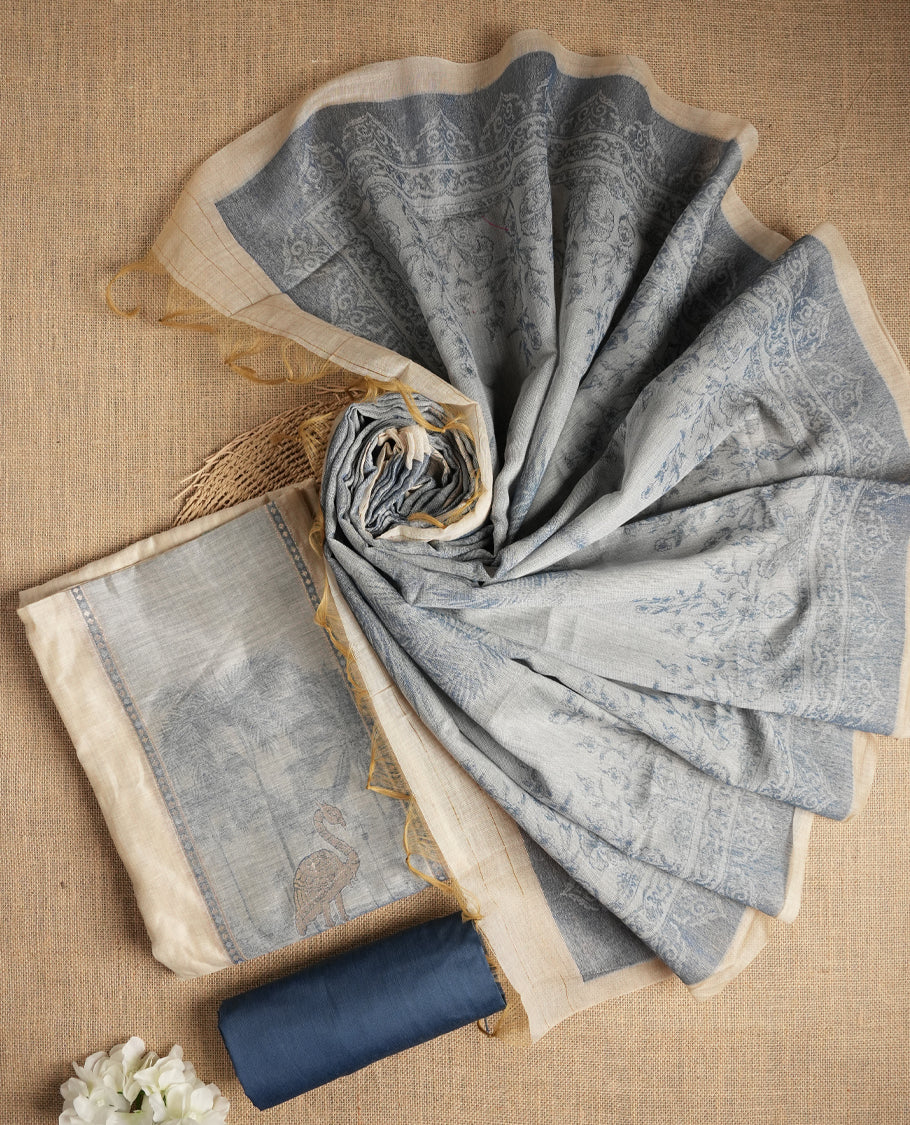 Beige & Blue colour suit material adorned with intricate woven patterns, bird print & subtle motifs, exuding ethnic grace & paired with a beautifully bordered dupatta and a matching plain bottom.