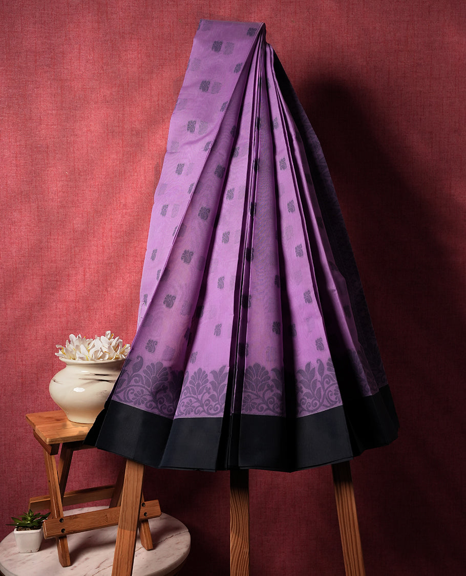 Lavender colour silk cotton saree featuring elegant floral zari motifs on the body, complemented by a rich contrast dark grey border and pallu with traditional woven detailing & Comes with a matching blouse piece.