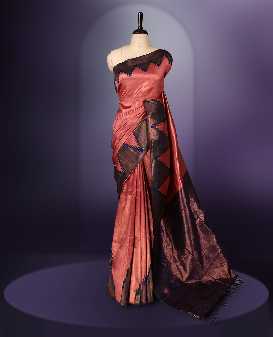 Peach pink saree highlighted with bold black and navy zigzag motifs along the border, complemented by a deep maroon blue pallu with a subtle sheen. Paired with a coordinated blouse piece.