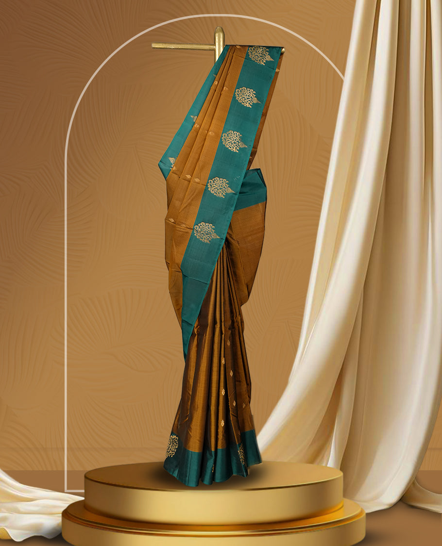 Coffee brown colour soft silk saree adorned with intricate golden zari motifs, teal green colour border for a perfect blend of tradition & Paired with a matching blouse.