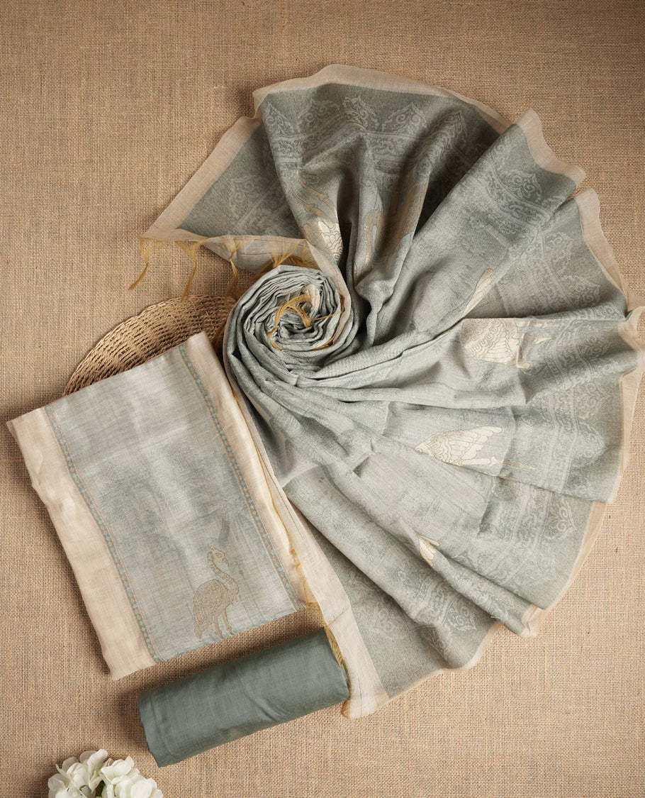 Beige & Pastel green colour suit material adorned with intricate woven patterns, bird print & subtle motifs, exuding ethnic grace & paired with a beautifully bordered dupatta and a matching plain bottom.