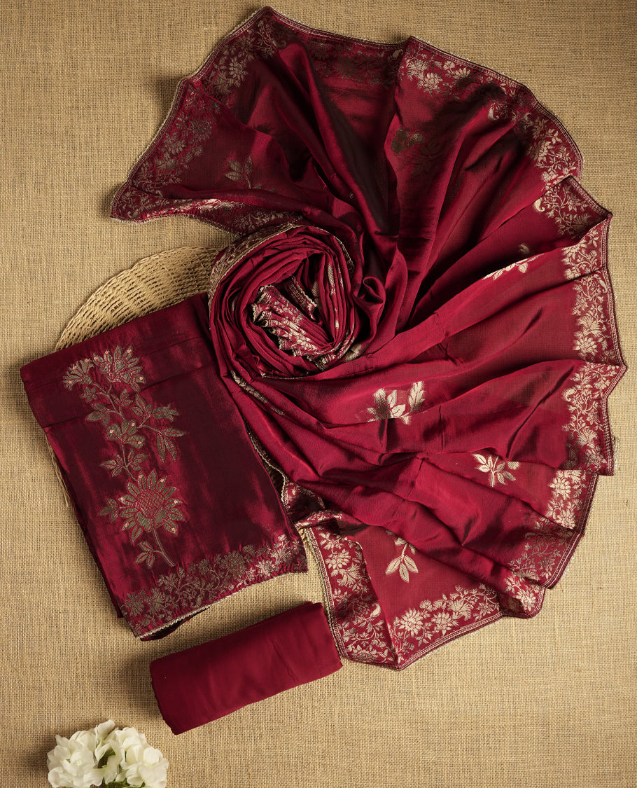 Elegant maroon colour suit material adorned with exquisite zari floral weaving, exuding regal charm & paired with a beautifully bordered dupatta and a matching plain bottom.