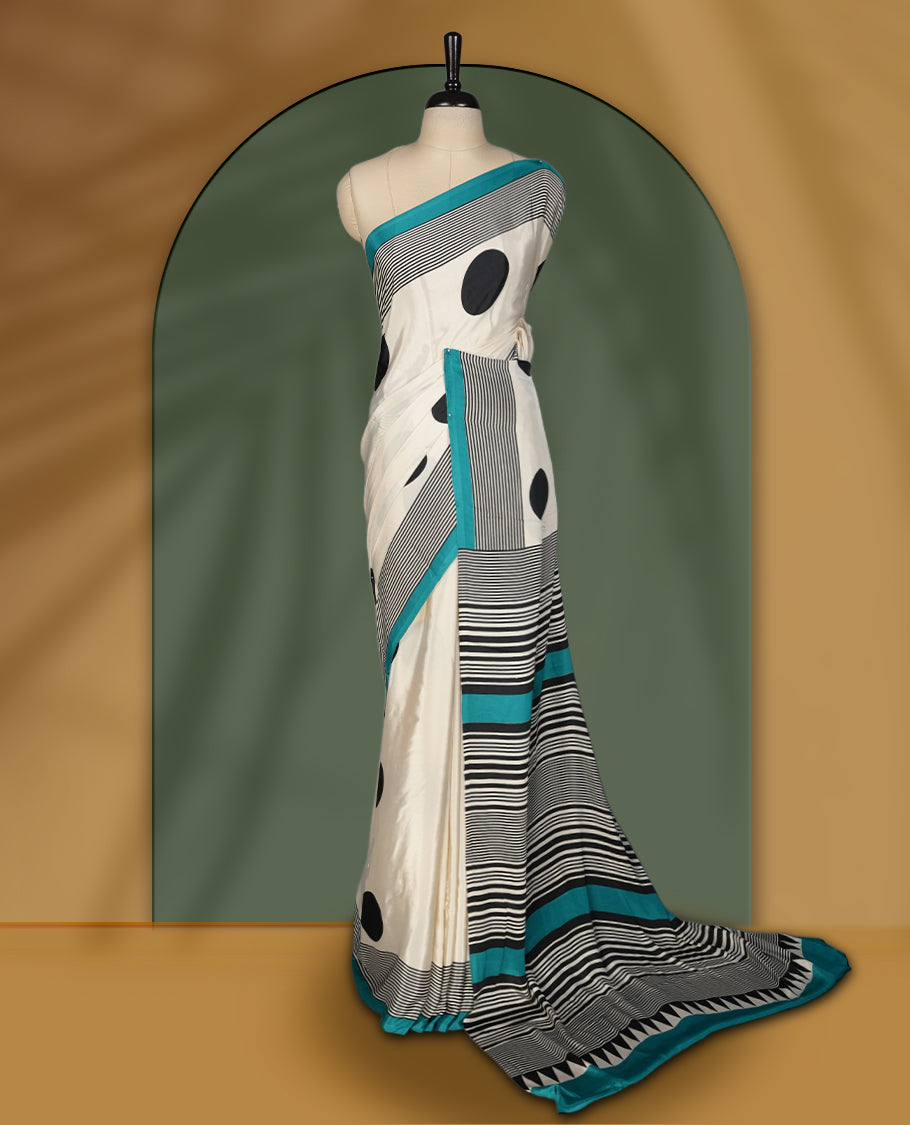 Ivory white colour saree with bold black polka dots and fine stripe detailing, elevated by a vibrant teal border & The striking pallu design adds charm. Lightweight and elegant, paired with matching blouse.
