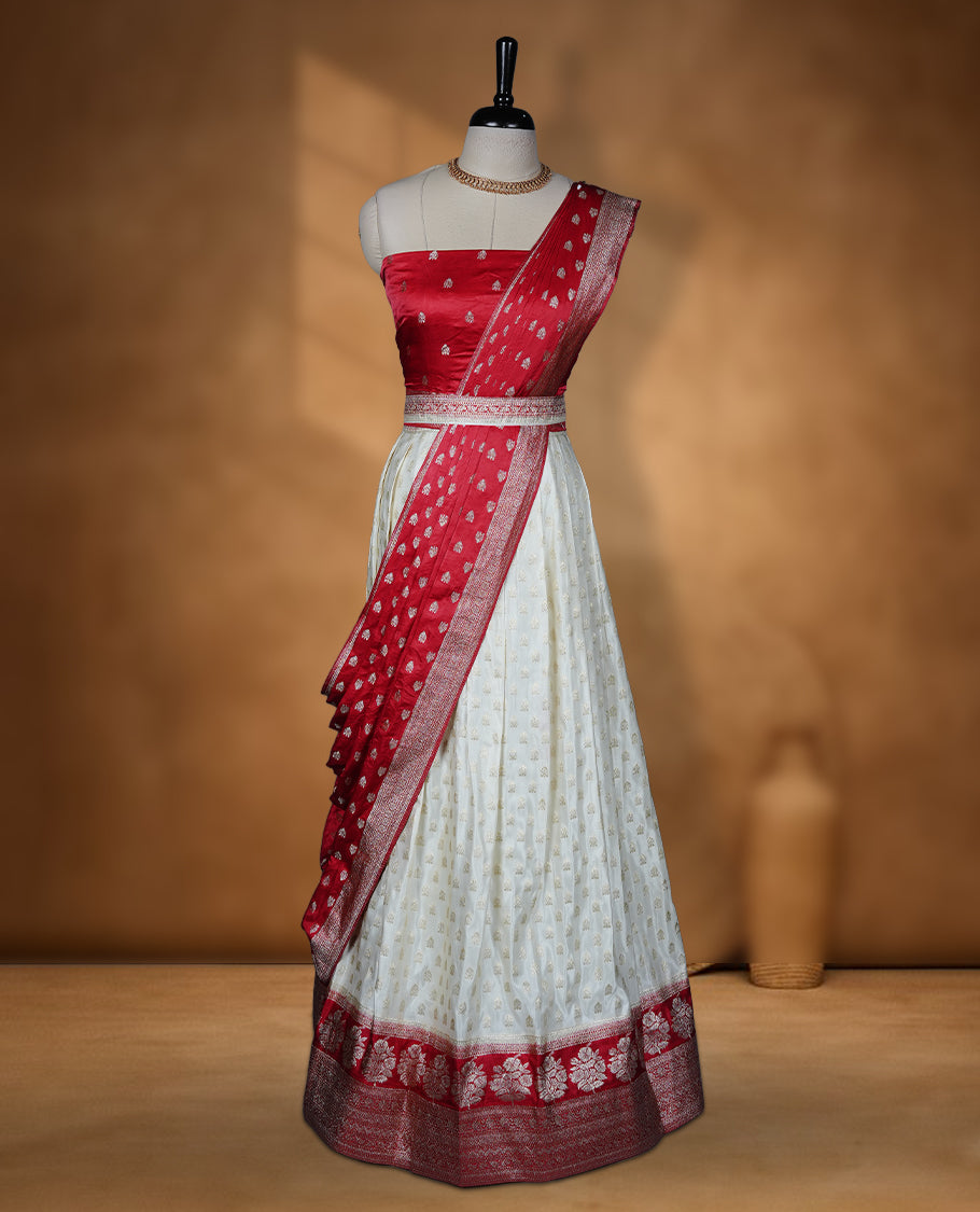 Off white semi banaras semi stitched dhavani set featuring gold zari motifs and contrast red colour and traditional border, unstitched gold zari blouse piece and matching Duptta.