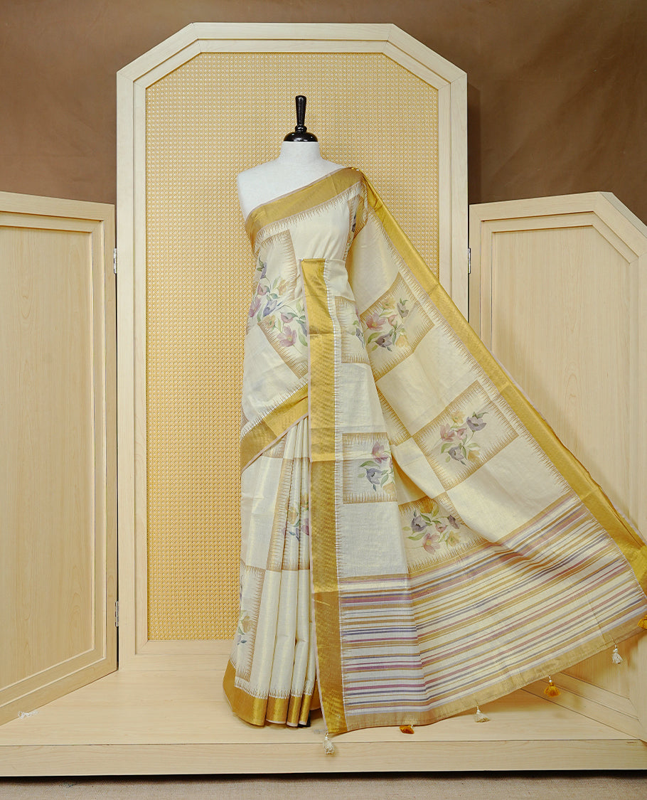 Cream Colour Tissue Kerala Saree Featuring Soft Floral Prints in a Classic Rectangle Pattern On Body, Enhanced with a Rich Gold Zari Border and a Striped Pallu. Finished with Elegant Tassels and Paired with a Matching Blouse Piece.