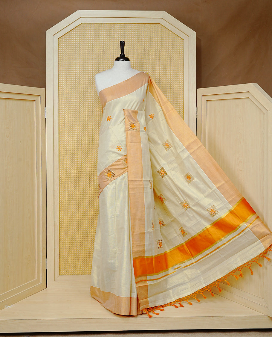 Cream Colour Tissue Kerala Saree Featuring Delicate Orange Floral Emboridery work Across The Body, Enhanced With A Light Orange Zari Border, A Vibrant Orange And Gold Zari Pallu, Finished With Orange Tassels, And A Matching Blouse Piece