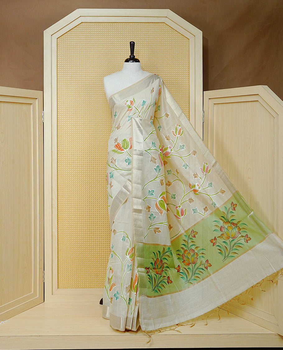 Cream Colour Tissue Kerala Saree Featuring Floral Kodi Threadwork Across The Body, Enhanced With A Light Gold Zari Border And A Light Green Floral Pallu, Finished With Gold Tassels And A Matching Blouse Piece