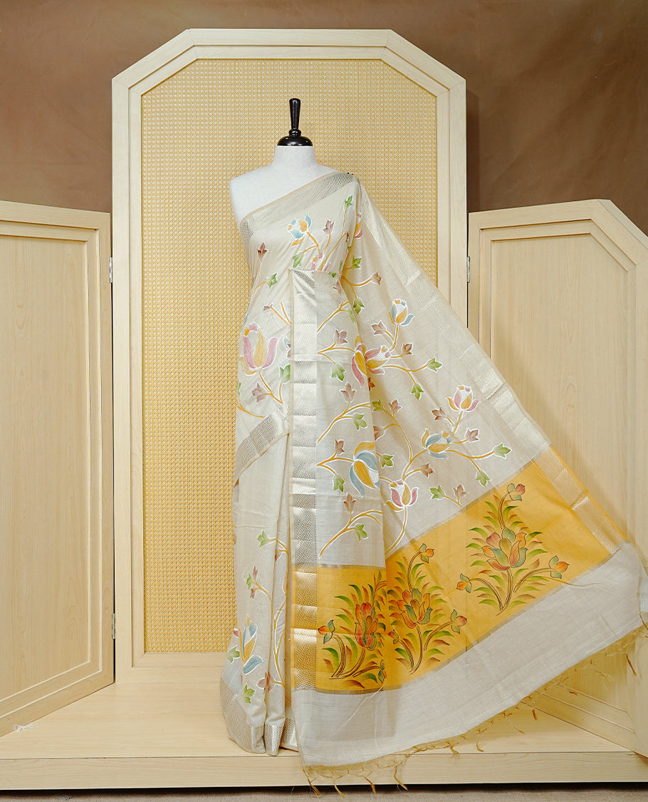 Cream Colour Tissue Kerala Saree Featuring Floral Kodi Threadwork Across The Body, Enhanced With A Light Gold Zari Border And A Yellow Floral Pallu, Finished With Gold Tassels And A Matching Blouse Piece