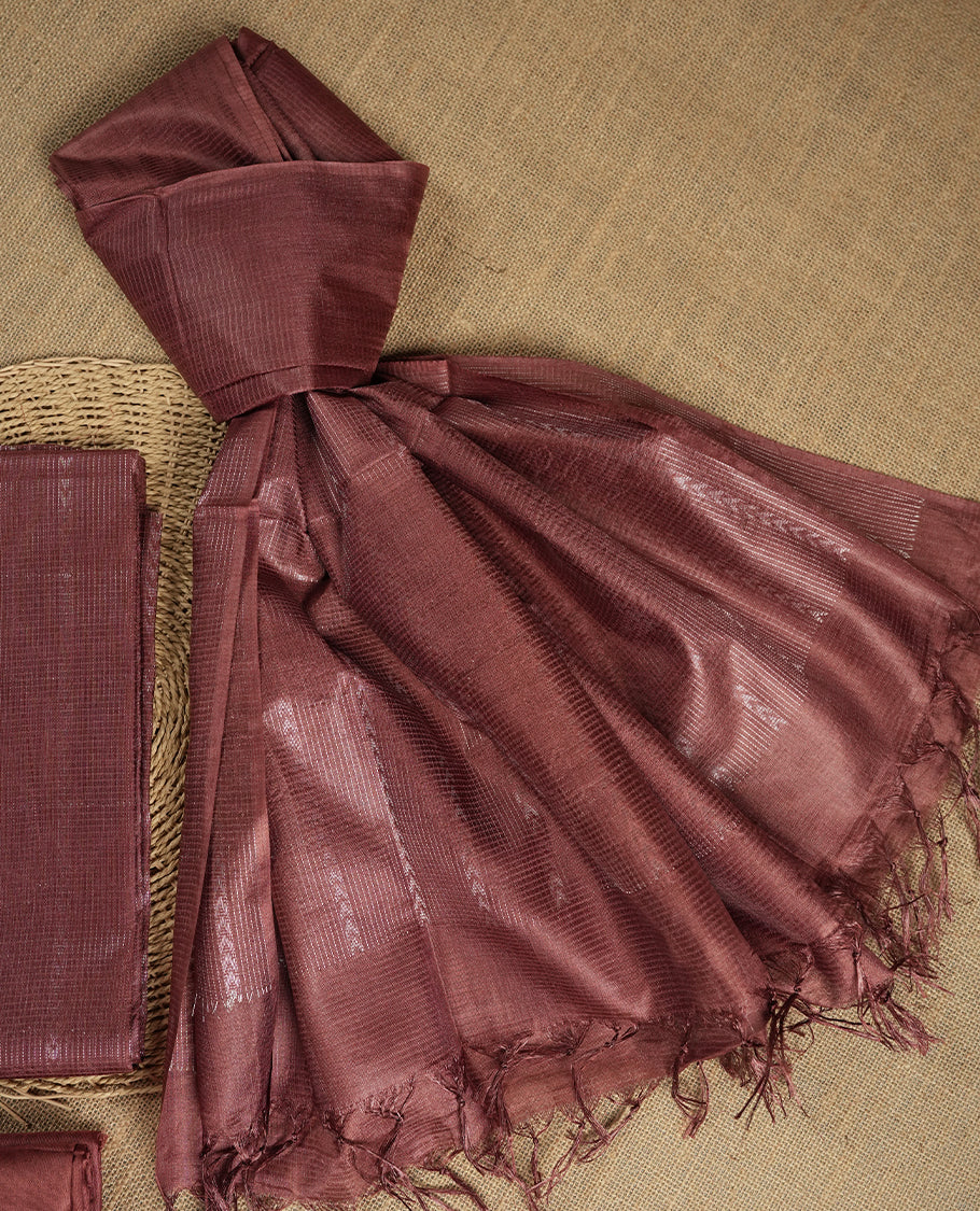Pastel chocolate brown colour tussar suit material featuring a subtle self copper zari woven vertical and stripped pattern on the body, paired with a lightweight matching dupatta with tassel edges and a plain bottom piece.