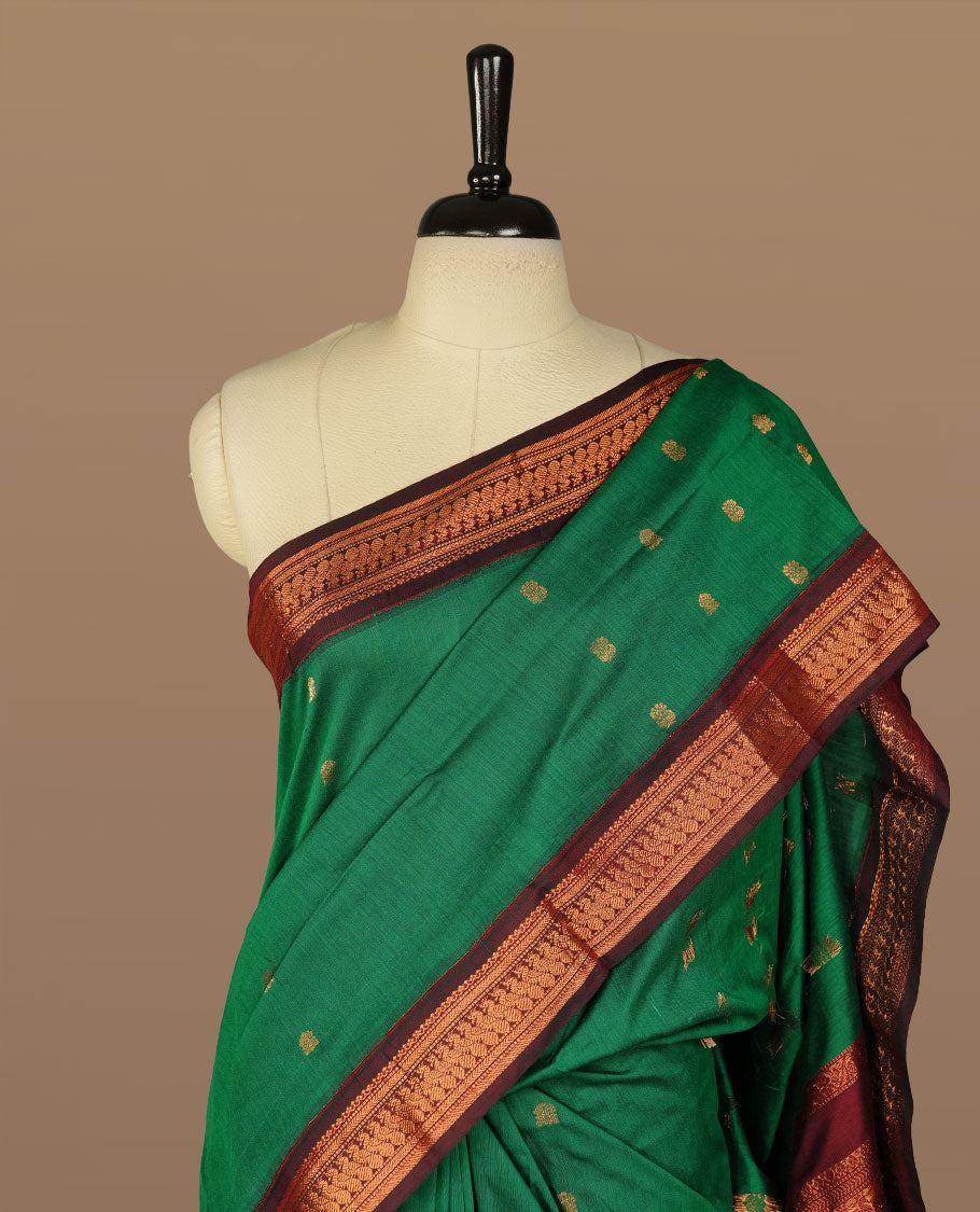 Green colour kalyani cotton saree featuring gold zari motifs on body, complemented by Maroon colour with Antique zari border, paired with matching blouse piece.