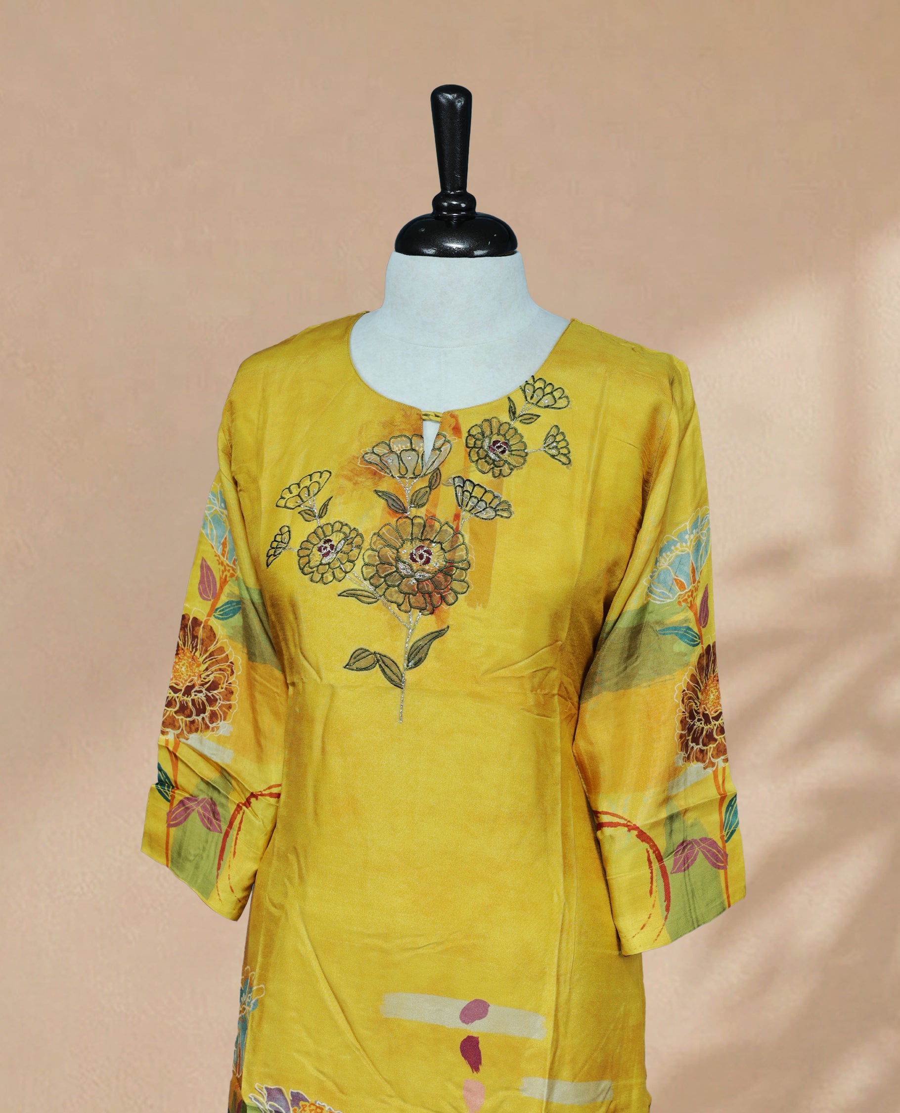 Mustard yellow Kurti featuring floral on the Body , a round neckline with a Floral Embroidery Work,A vibrant floral printed 3/4 sleeves, and a colourful floral and abstract print along the lower portion.