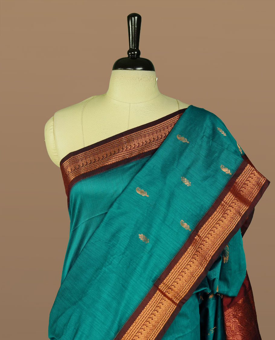 Peacock green colour kalyani cotton saree featuring gold zari motifs on body, complemented by Maroon colour with Antique zari border, paired with matching blouse piece.