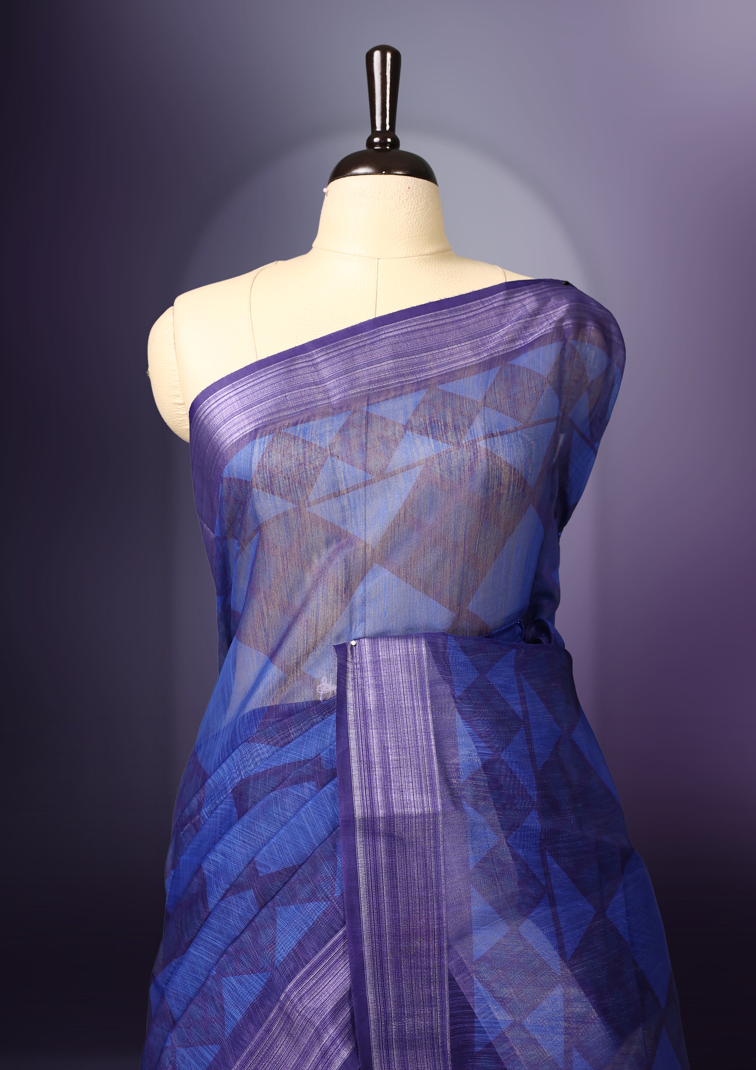 Blue saree adorned with geometric woven patterns across the body, accentuated with a subtle striped border, and a pallu featuring circular motifs with delicate tassel detailing, paired with a matching blouse.
