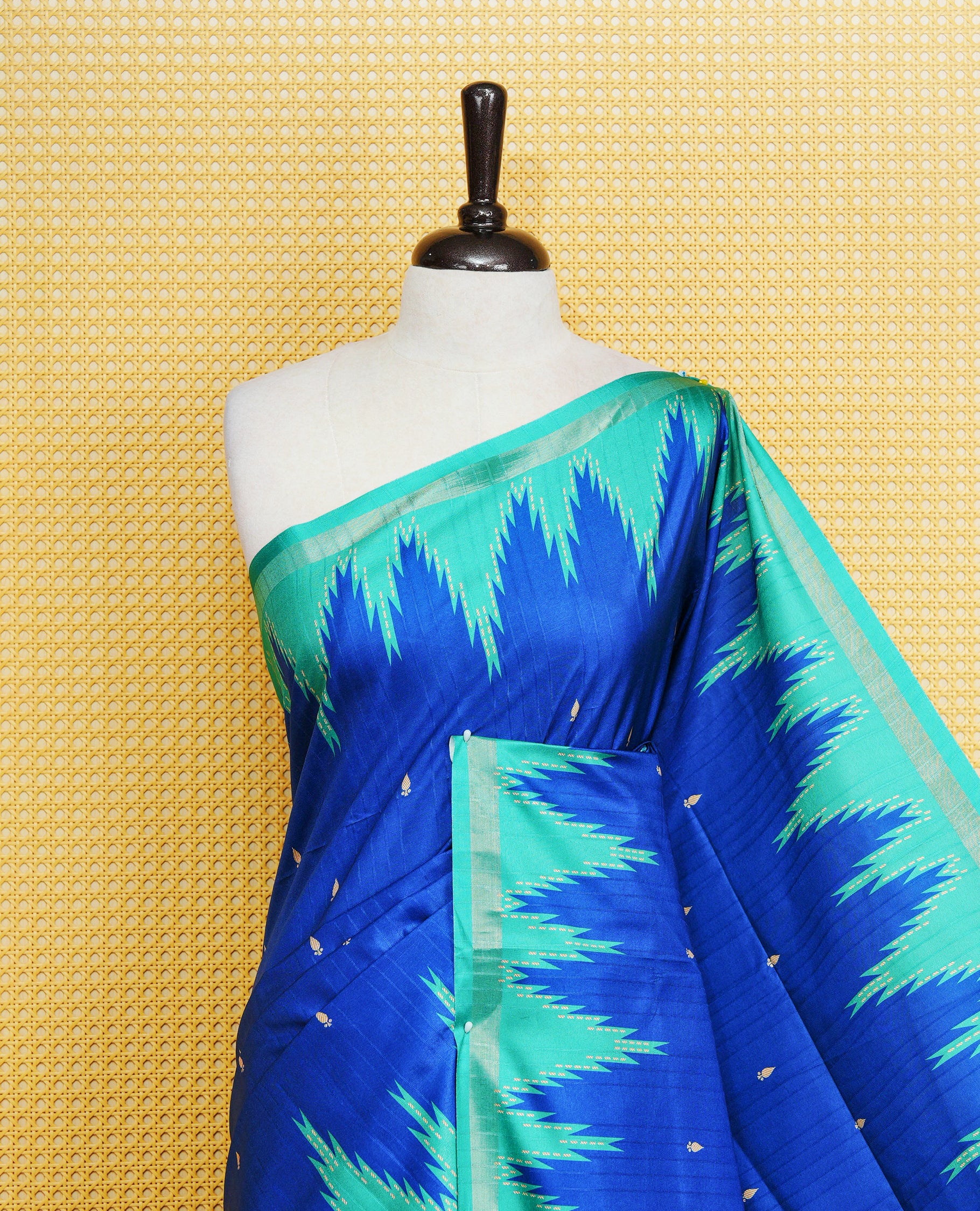 Royal Blue and Teal Green Colour Kattan silk saree featuring buttas all over the body, a temple-designed border & a contrasting striped pallu with tassels. Paired with a matching contrast-striped blouse piece.
