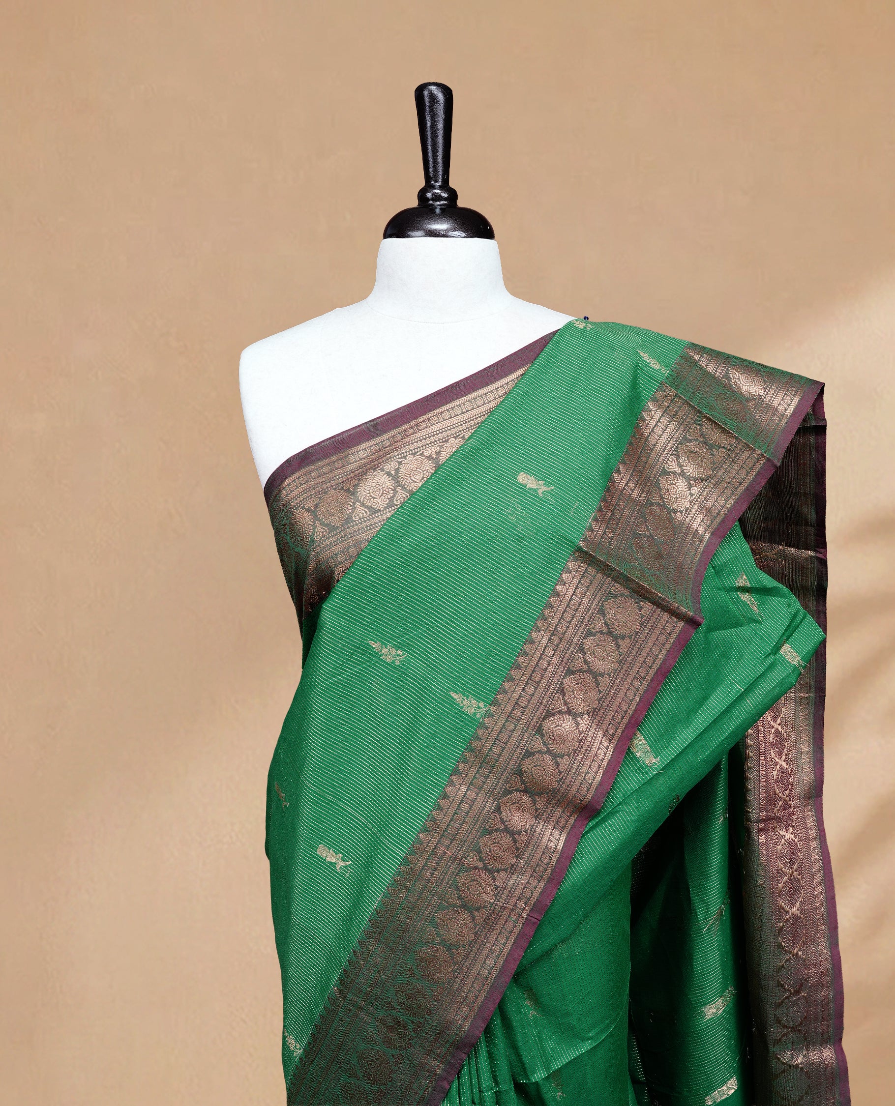 Green colour chettinad cotton saree featuring gold zari stripes & motifs on body, complemented by Contrast Maroon colour with zari border, paired with matching blouse piece.