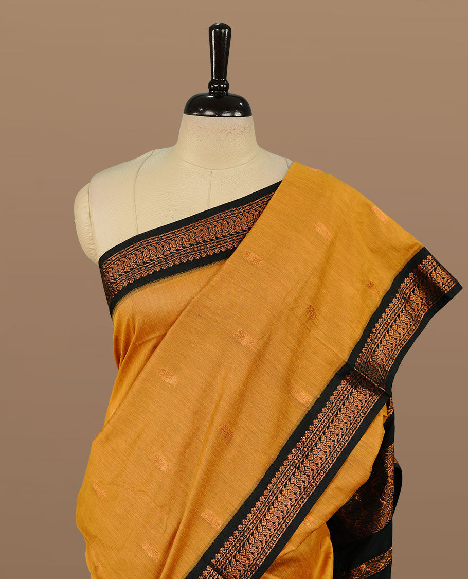 Mustard colour kalyani cotton saree featuring Elegant plain body, complemented by Black colour with Antique zari border, paired with matching blouse piece.