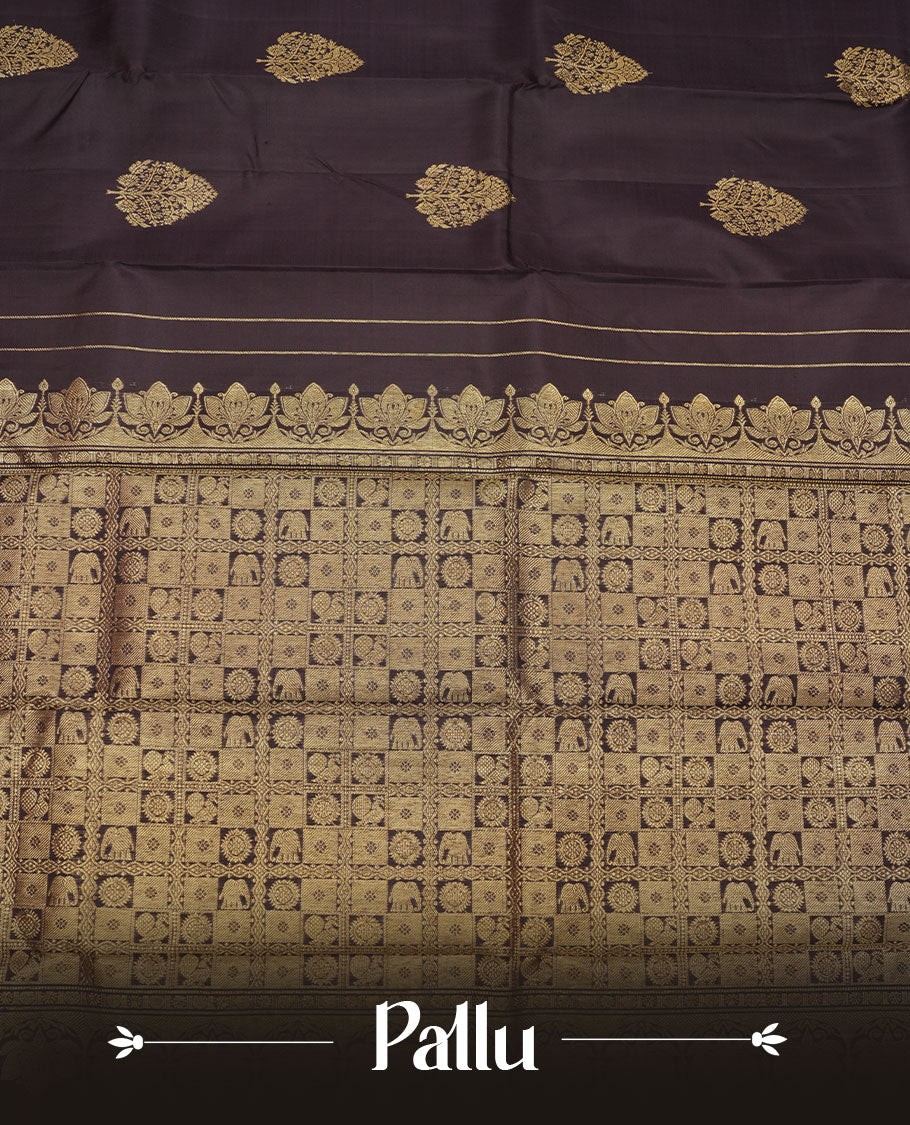 Deep coffee brown colour pure traditional Kancheepuram silk saree adorned with elegant zari tree motifs across the body, complemented by a rich zari woven border with a subtle green edge, paired with a matching blouse piece.