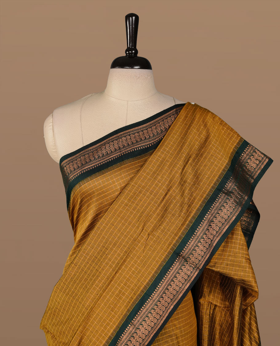 Mustard colour kalyani cotton saree featuring gold zari check pattern on body, complemented by green colour with Antique zari border, paired with matching blouse piece.