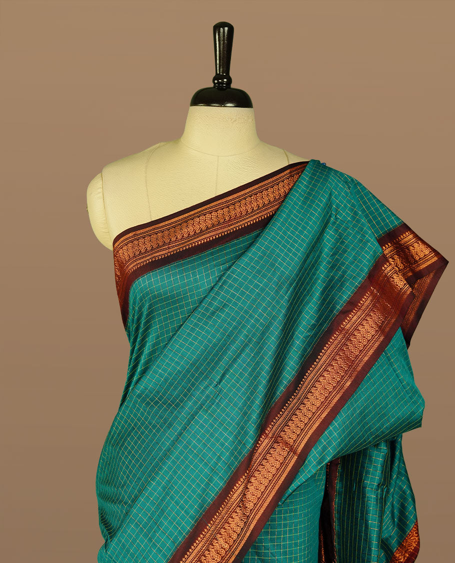 Teal green colour kalyani cotton saree featuring gold zari check pattern on body, complemented by Maroon colour with Antique zari border, paired with matching blouse piece.