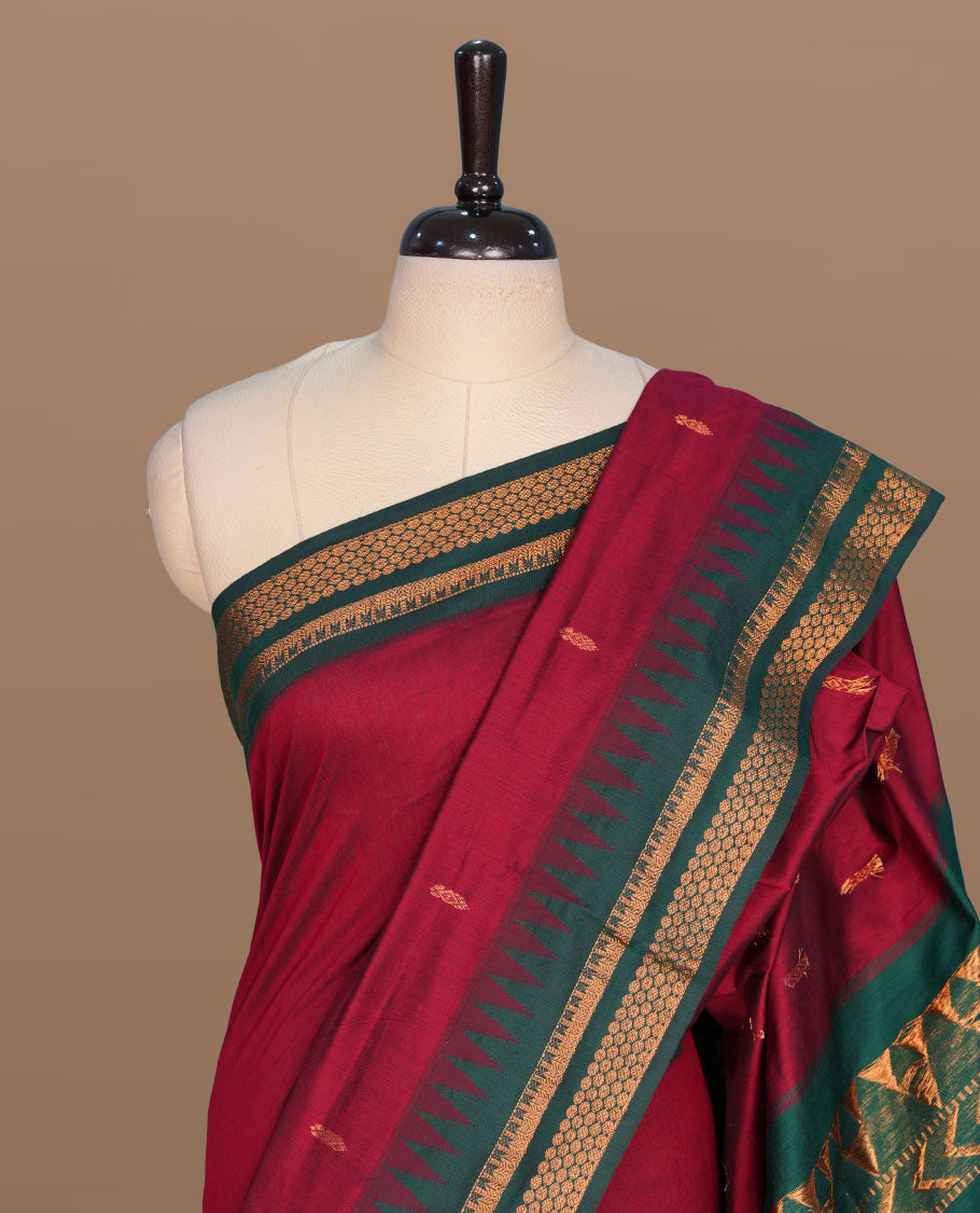 Maroon colour kalyani cotton saree featuring gold zari motifs on body, complemented by contrast maroon color with gold zari pattern border , paired with matching blouse piece.