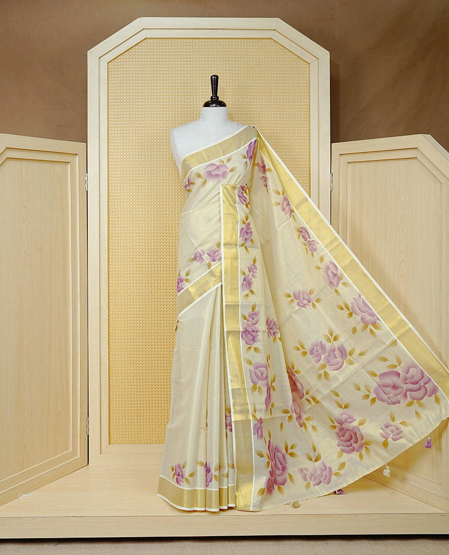 Cream Colour Tissue Kerala Saree Featuring Digital Purple Rose Prints Across The Body, Enhanced With A Gold Zari Border , Finished With Purple & Cream Tassels And A Matching Blouse Piece