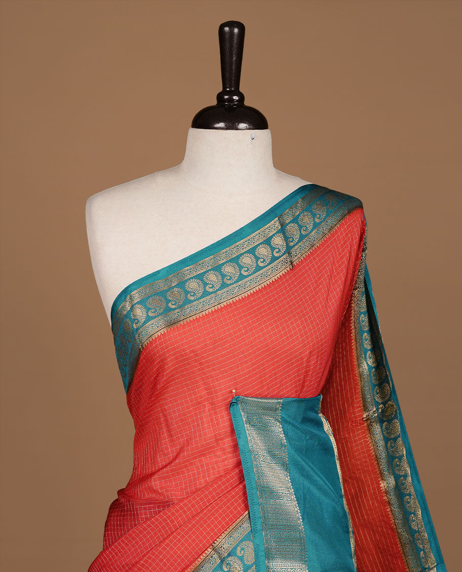 Red colour semi georgette saree featuring gold zari check pattern on body, complemented by contrast teal colour with zari border, paired with matching blouse piece.