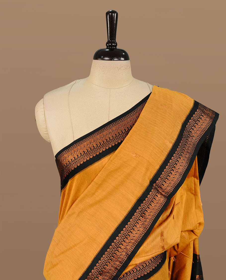 Mustard colour kalyani cotton saree featuring Elegant plain body, complemented by Black colour with Antique zari border, paired with matching blouse piece.
