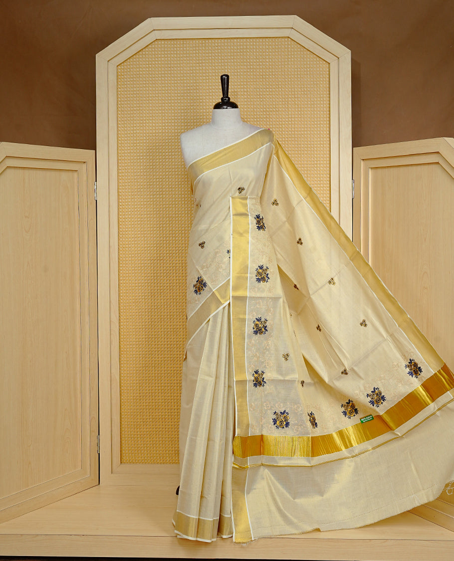 Cream colour Tissue kerala saree featuring Embroidery buttas on body, complemented by Floral kodi thread work & kasavu kara, comes with matching blouse piece.