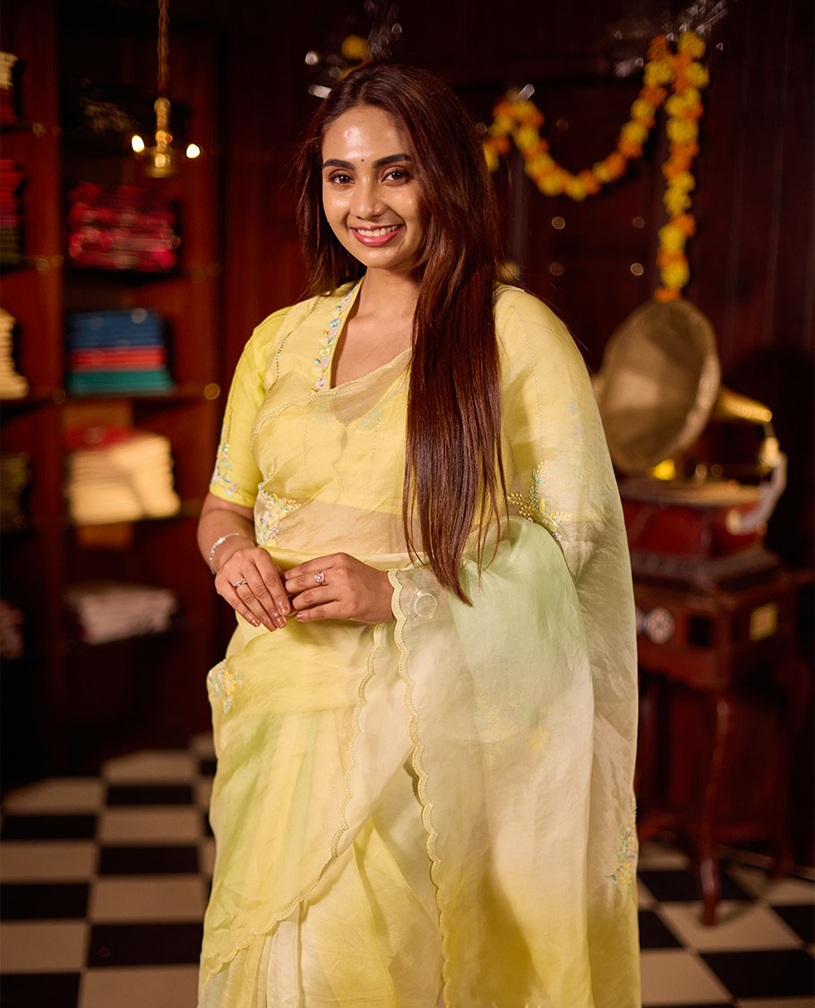 Pastel yellow colour premium organza saree featuring delicate floral hand embroidery with beads and sequins, finished with an elegant scalloped border and paired with a matching embroidered blouse.