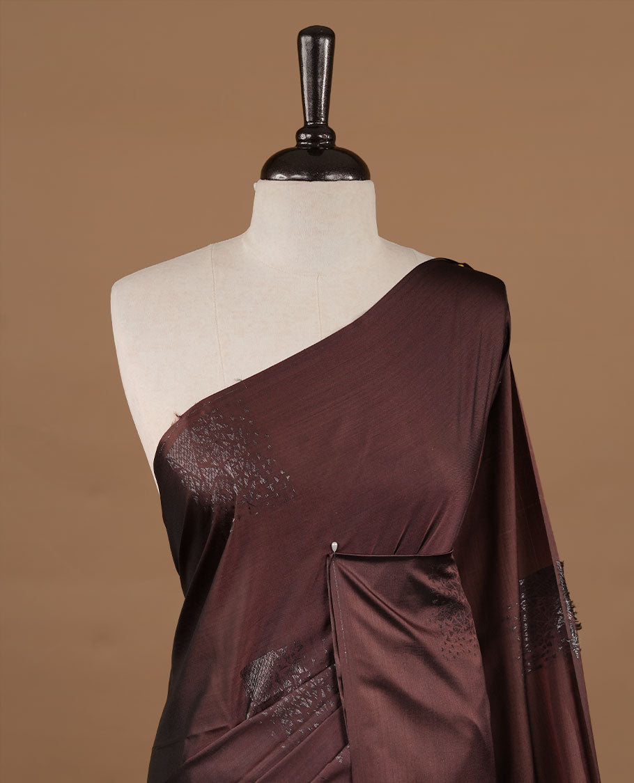 Chocolate colour soft silk saree features a sleek borderless design with intricate antique zari motifs, flowing into a striking contrast burnt orange and a matching blouse piece.