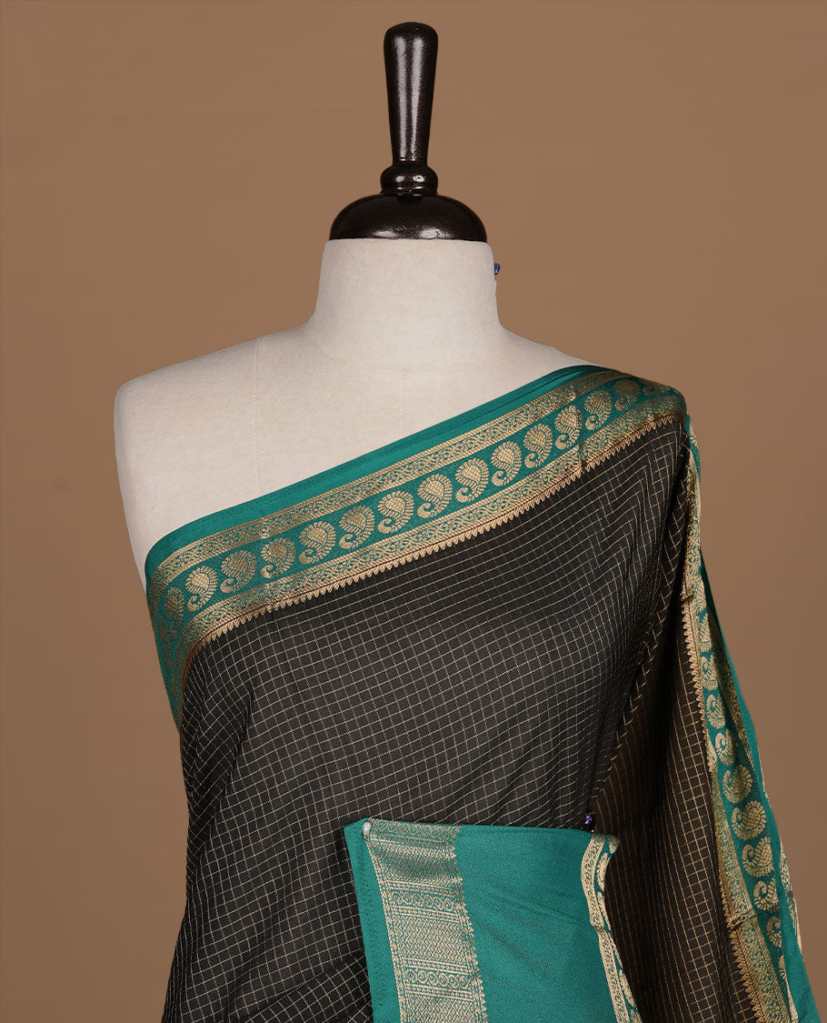 Black colour semi georgette saree featuring gold zari check pattern on body, complemented by contrast green colour with zari border, paired with matching blouse piece.