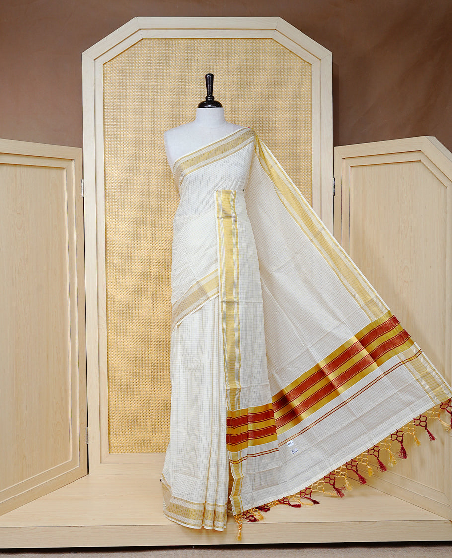 Cream colour Cotton kerala saree featuring Gold zari Checks on body, complemented by Gold zari border & Maroon with gold zari Pallu, paired with matching blouse piece.