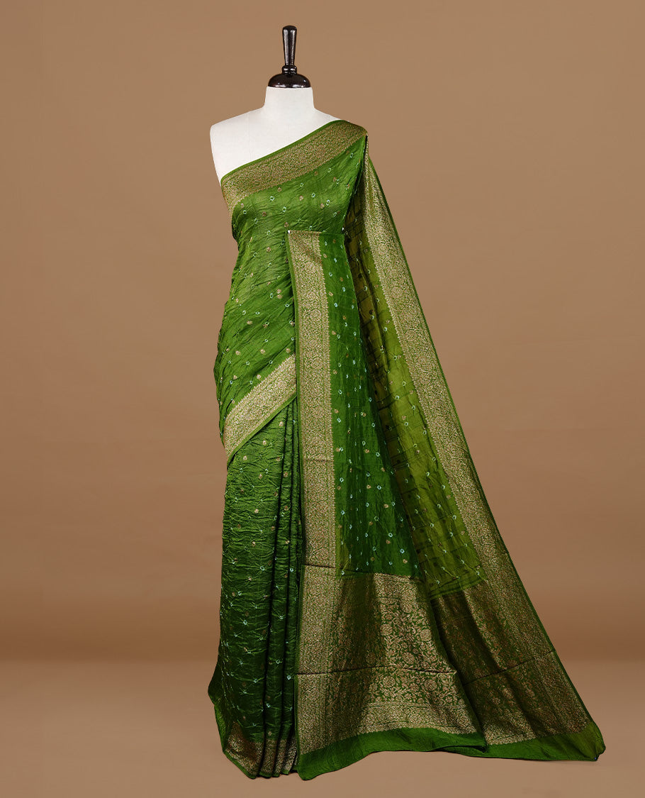 Green colour Banarasi Bandhani silk saree featuring intricate antique zari circle Buttas across the body, complemented by an elegant antique zari border. Comes paired with a matching blouse piece