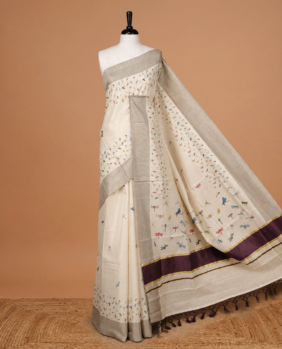 Cream Colour Tissue Kerala Saree Featuring Plain Body ,Complemented By Maroon Zari With Dragonfly Printed Border ,Enhance By A Maroon With Gold Zari Pallu ,Paired With A Matching Blouse Piece.