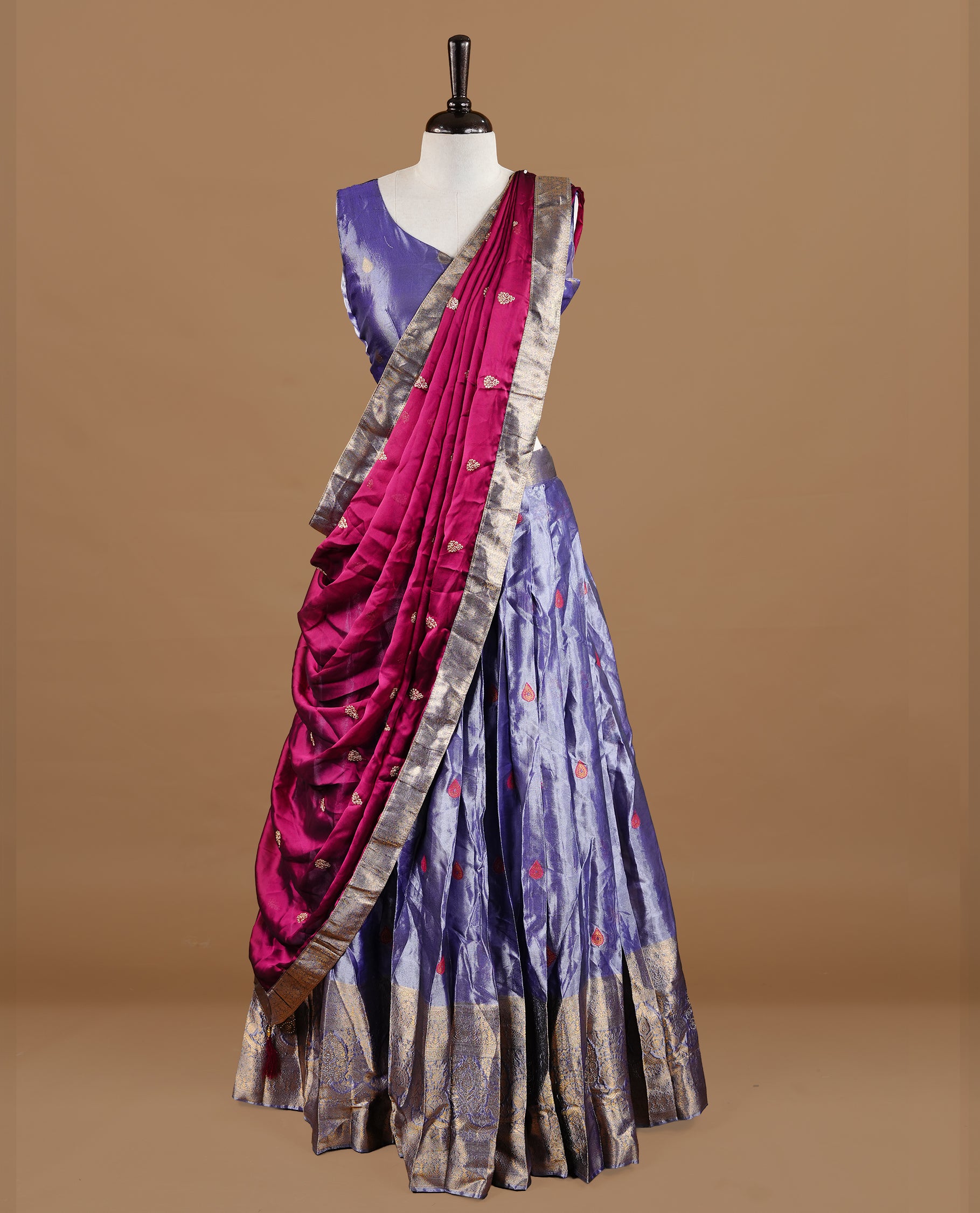 Lavender colour featuring lavender colour skirt highlighting gold zari motifs & border, contrast maroon dupatta, with matching stitched blouse.