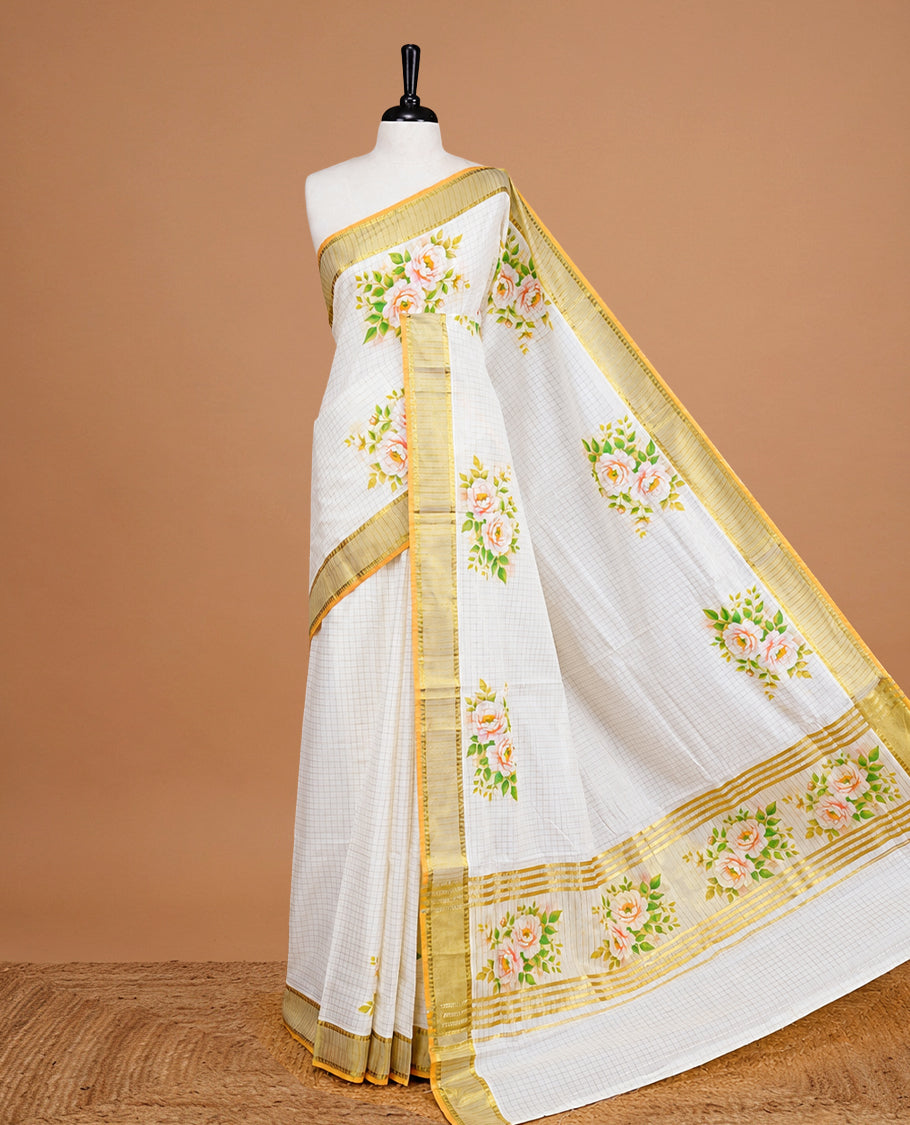 Cream Colour Kerala Saree Featuring Gold Zari Checks On The Body, Enhanced By A Gold Zari Border With Floral Prints And A Matching Pallu, Paired With A Matching Blouse Piece.