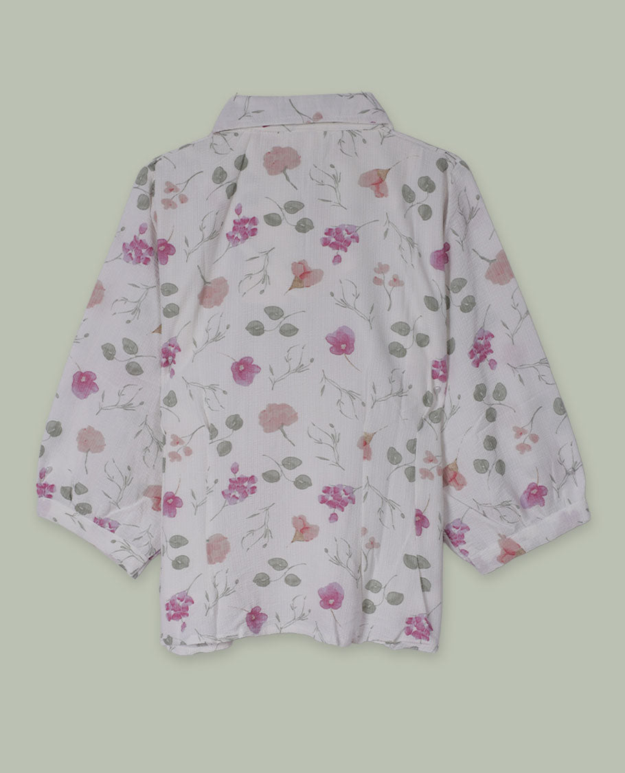 White floral printed shirt top with collared neckline, three-quarter sleeves, and front button placket framed by embroidered lace detailing.