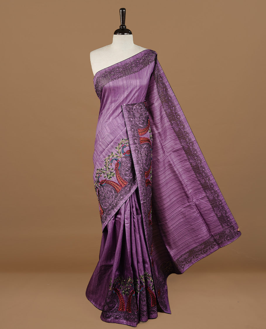 Purple colour Semi Tussar silk saree features an intricate cutwork embroidered peacock motifs on border, paired with a matching unstitched blouse piece.