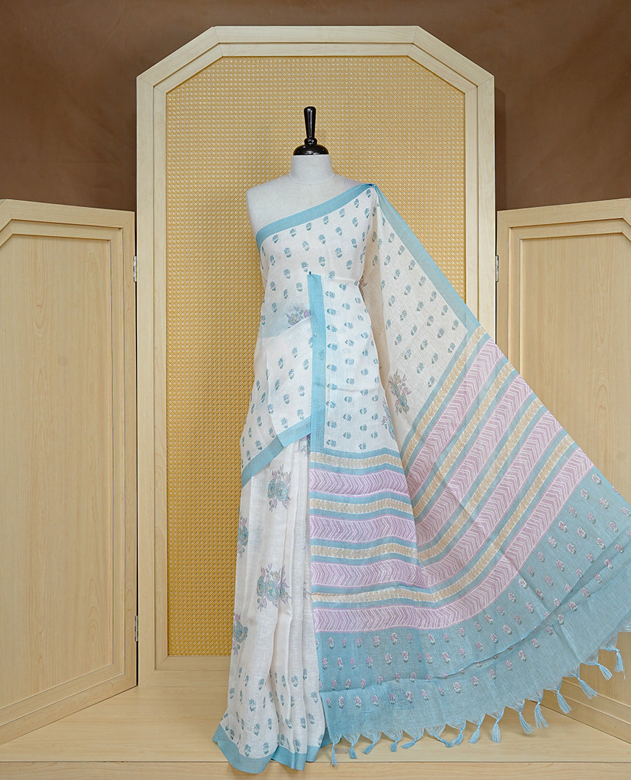 Cream colour semi linen saree featuring Floral printed buttas on body, complemented by contrast Blue colour border, comes with matching blouse piece.
