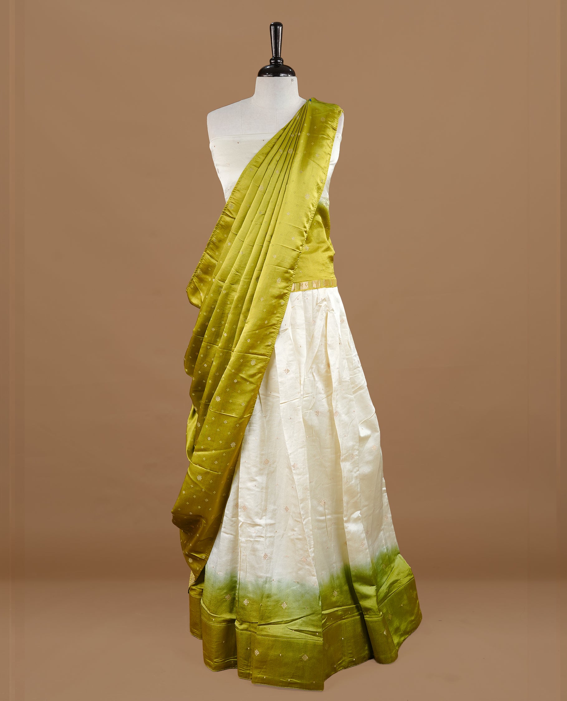 Off white colour semi stitched half saree featuring elegant zari buttas on the body, paired with a contrast pastel green border and matching striped dupatta,paired with matching blouse piece.