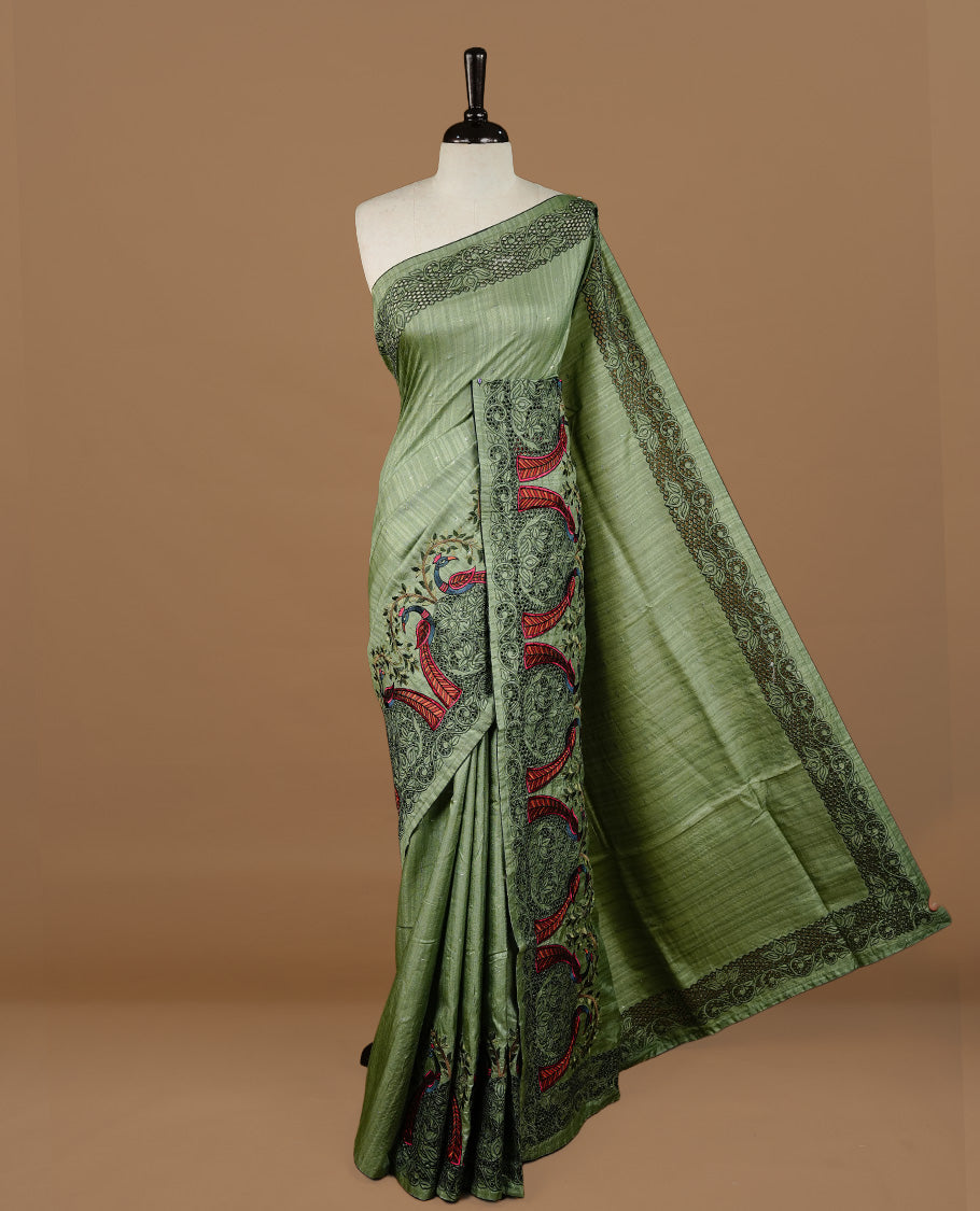 Green colour Semi Tussar silk saree features an intricate cutwork embroidered peacock motifs on border, paired with a matching unstitched blouse piece.