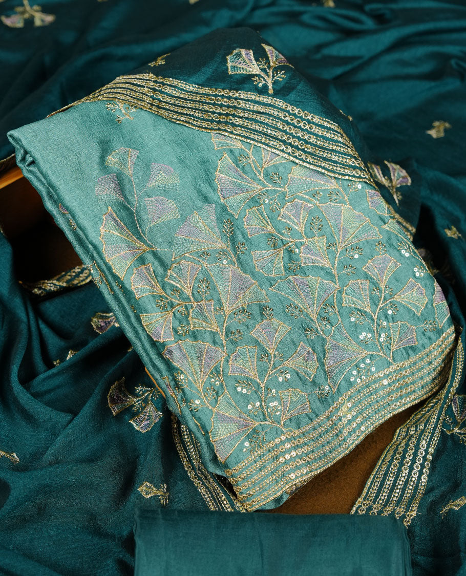 pastel teal colour olive colour churidar material with subtle mirror and thread embroidery, finished with delicate border detailing and paired with a matching plain bottom and dupatta.