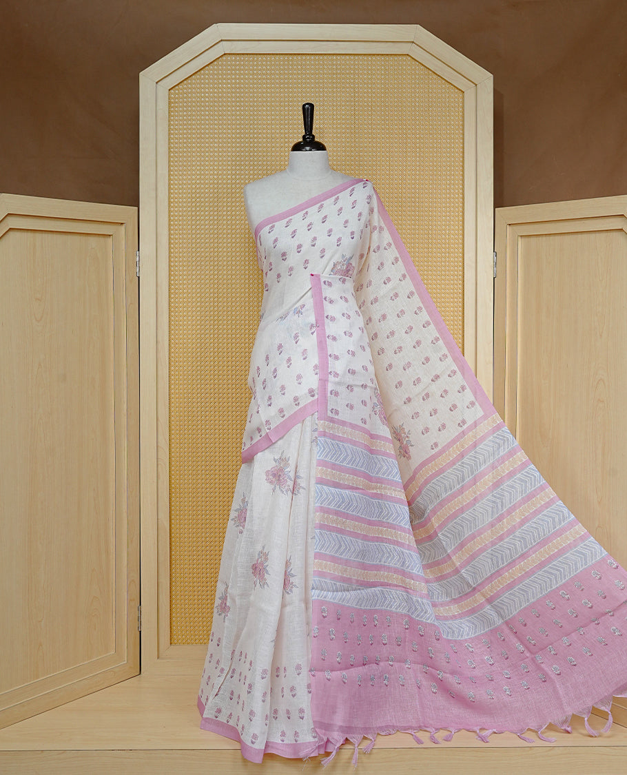 Cream colour semi linen saree featuring Floral printed buttas on body, complemented by contrast Pink colour border, comes with matching blouse piece.