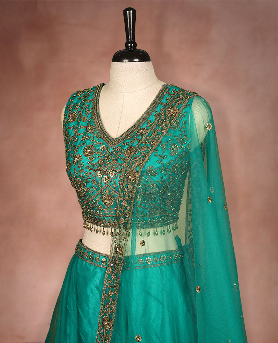Green colour lehenga set with stitched sleeveless Antique thread embroidered & beats worked blouse featuring sheer neckline, matching stitched flared lehenga, and plain sheer dupatta.